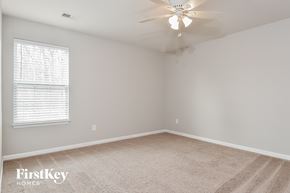 Greensboro house for rent - a bedroom with a carpeted floor and a ceiling fan