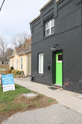 Guelph apartment for rent - a black house with a green door and a sign on the sidewalk