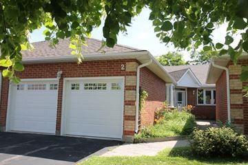 Cambridge apartment for rent - A house with a white garage door is seen through the leaves.