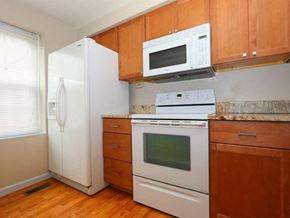 Maineville house for rent - A kitchen with a white refrigerator, white oven, and wooden cabinets.