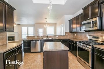 Fort Worth house for rent - A kitchen with black cabinets and a stainless steel dishwasher.
