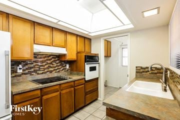 Phoenix house for rent - A kitchen with wooden cabinets and a stone backsplash.