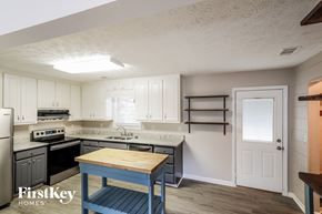 Winder house for rent - a kitchen with white cabinets and black appliances and a blue table