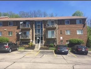 Cincinnati apartment for rent - A parking lot in front of a brick apartment building with cars parked.