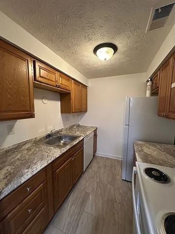 Cincinnati apartment for rent - A kitchen with a white refrigerator and brown cabinets.