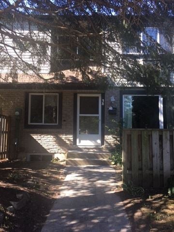 Guelph apartment for rent - A house with a white door and a window is surrounded by a wooden fence.