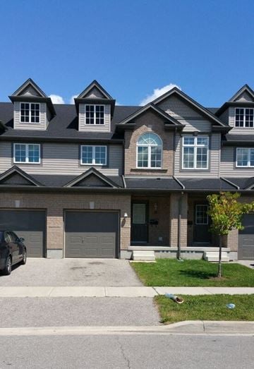 Guelph apartment for rent - A grey house with a black car parked in front.