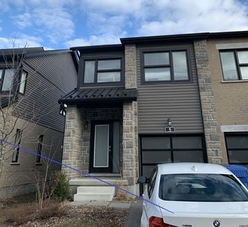 Guelph apartment for rent - A white BMW is parked in front of a grey house.