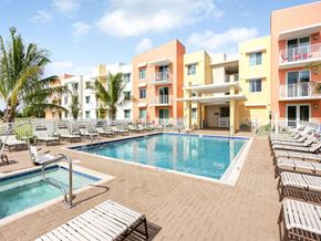 Riviera Beach apartment for rent - a swimming pool with lounge chairs in front of an apartment building