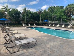 Lake Worth apartment for rent - A pool surrounded by lounge chairs and umbrellas.