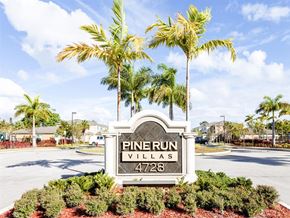 Lake Worth apartment for rent - A sign for Pine Run Villas stands in front of a row of palm trees.