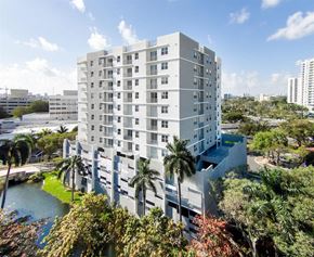 Miami apartment for rent - a large white building with palm trees and a body of water