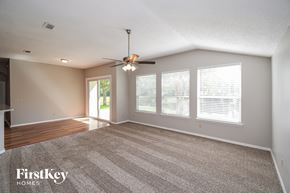 Jacksonville house for rent - an empty living room with a ceiling fan and windows
