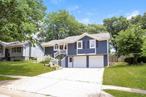 Kansas City house for rent - A two-story house with a garage and a flag on the front porch.