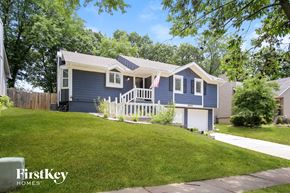 Kansas City house for rent - A blue house with a white porch and a flag on it.