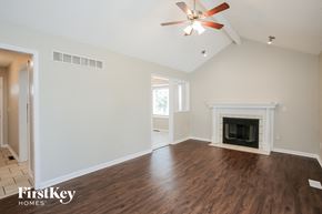 Kansas City house for rent - A spacious living room with a fireplace and a ceiling fan.