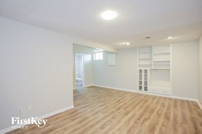 Kansas City house for rent - A spacious empty room with wooden flooring and white walls.