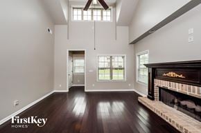 Odenville house for rent - A spacious living room with a fireplace and a view of the backyard through the window.