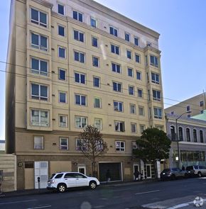 San Francisco apartment for rent - A white car is parked in front of a tan building.