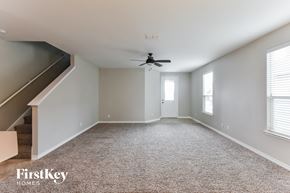 San Antonio house for rent - a carpeted living room with a ceiling fan and a staircase