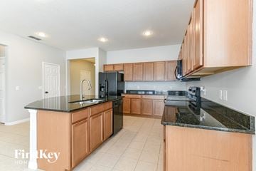 Kissimmee house for rent - A kitchen with wooden cabinets and black countertops.