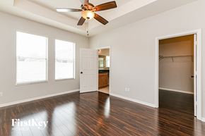 Kissimmee house for rent - A spacious room with a ceiling fan and wooden floors.