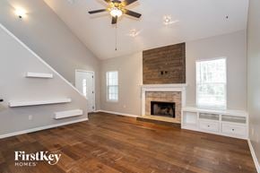 Loganville house for rent - an empty living room with a fireplace and a ceiling fan