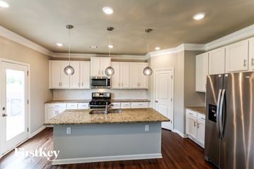 Flowery Branch house for rent - a kitchen with white cabinets and a granite counter top