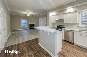 Dallas house for rent - an open kitchen and living room with white cabinets and a white counter top