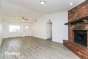 Mesa house for rent - A spacious room with a brick fireplace and wooden flooring.