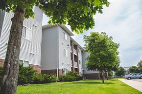 Ames apartment for rent - a street view of a building with a tree in the grass