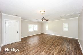 Douglasville house for rent - the living room of an empty house with wood floors and a ceiling fan