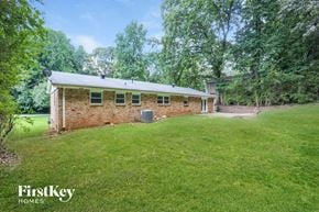 Douglasville house for rent - a small brick house with a green lawn and trees