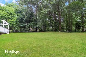 Canton house for rent - A lush green lawn with trees and a white structure in the background.