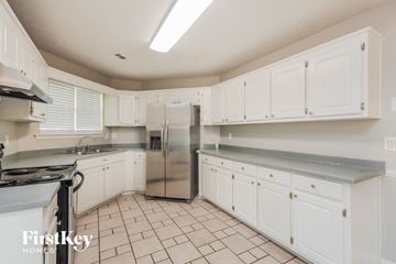 Covington house for rent - a kitchen with white cabinets and a stainless steel refrigerator