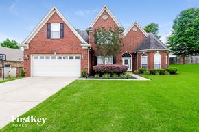 Cordova house for rent - A brick house with a white garage door and a large lawn.