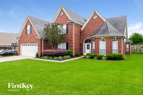 Cordova house for rent - A brick house with a white garage door and a tree in front.