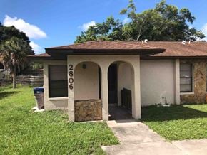 Bradenton house for rent - a small tan house with a driveway and a gate