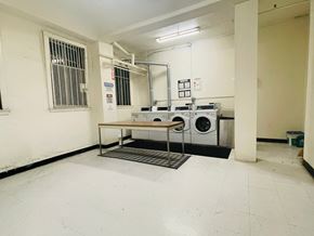 San Francisco apartment for rent - A laundry room with a washer and dryer, a table, and a metal grate on the floor.