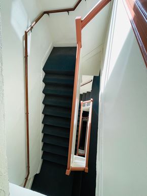 San Francisco apartment for rent - A staircase with a black carpet and wooden handrail.