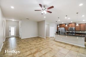 Jacksonville house for rent - an empty living room with a kitchen and a ceiling fan