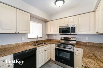 Fort Myers house for rent - A kitchen with a black dishwasher and a black microwave above the stove.