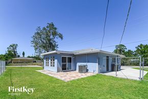 Fort Myers house for rent - A blue house with a fence and trees in the background.