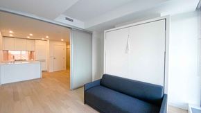 Vancouver apartment for rent - A black couch sits in a white room with a kitchen in the background.