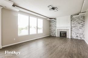 Kansas City house for rent - A spacious living room with a stone fireplace and wooden flooring.