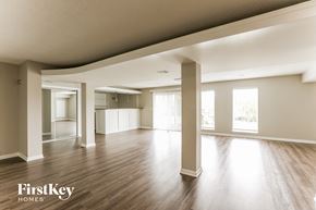 Kansas City house for rent - A spacious room with wooden floors and white walls, with a FirstKey Homes logo in the corner.