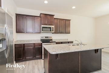 Winston-Salem house for rent - a kitchen with dark wood cabinets and granite counter tops and stainless steel appliances