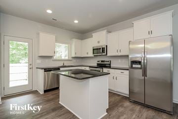 Winston-Salem house for rent - a kitchen with white cabinets and stainless steel appliances