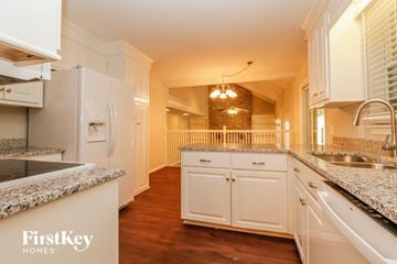 Summerville house for rent - A kitchen with white cabinets and a granite countertop.
