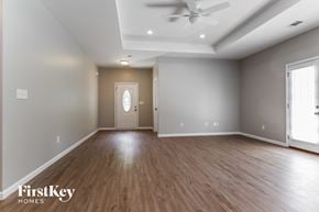 Dacula house for rent - A spacious room with wooden floors and a ceiling fan.